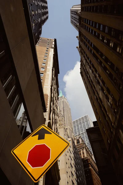 Vista de ángulo bajo de la señal de tráfico, edificios altos y rascacielos en la ciudad de Nueva York, atmósfera urbana - foto de stock