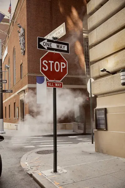 Vapor cerca de señales de tráfico y edificios antiguos en el centro de la ciudad de Nueva York, atmósfera metropolitana - foto de stock