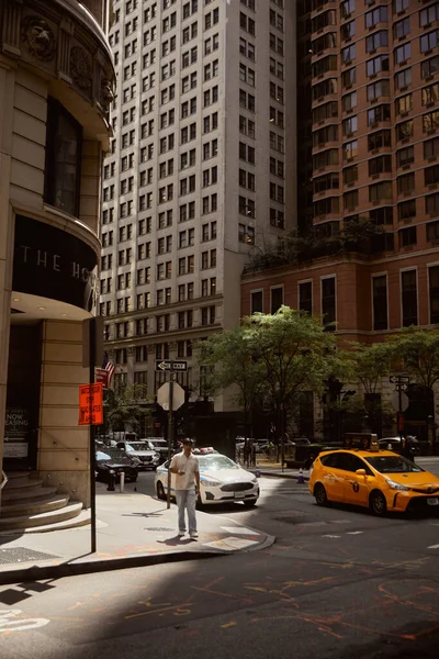НЬЮ-ЙОРК, США - 26 ноября 2022 года: человек идет по тротуару рядом с перекрестком с движущимися автомобилями — стоковое фото