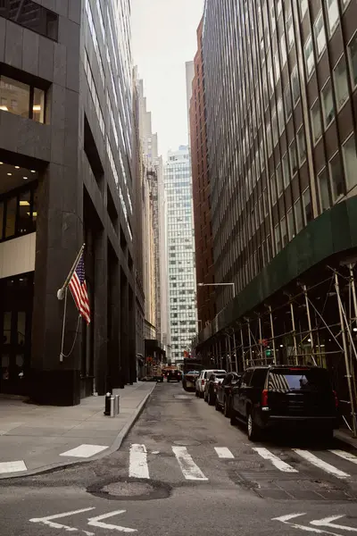 Voitures garées sur la chaussée de la rue étroite près des bâtiments modernes sombres dans la ville de New York, scène urbaine — Photo de stock