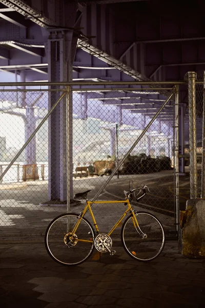 Gelbes Fahrrad in der Nähe von Metallnetzzaun über Brücke in New York City, moderne Metropolszene — Stockfoto