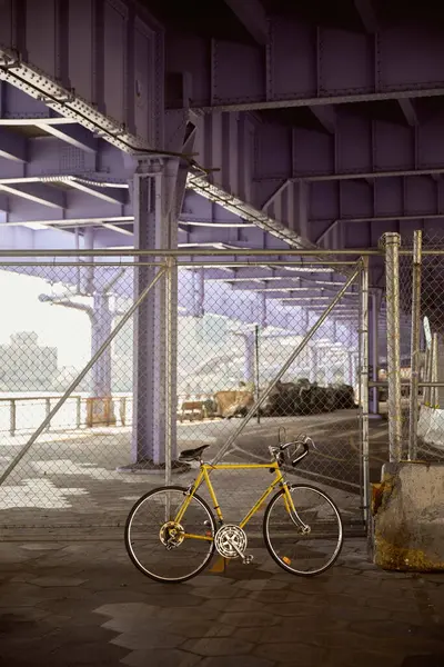 Жовтий велосипед біля металевої сітки паркан над мостом в Нью-Йорку, сучасна сцена мегаполісу — стокове фото