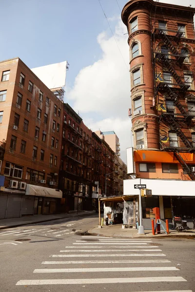 Edificio de época con escalera de incendios cerca de paso peatonal en la esquina de la calle en la ciudad de Nueva York - foto de stock