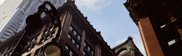 Bandeira, visão de ângulo baixo de lanterna perto de edifícios modernos e vintage contra o céu na cidade de Nova Iorque — Fotografia de Stock