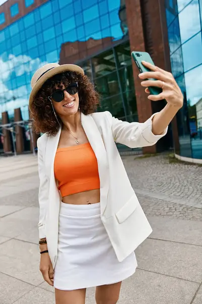 A young woman takes a selfie in a stylish outfit while exploring the city. — Stock Photo