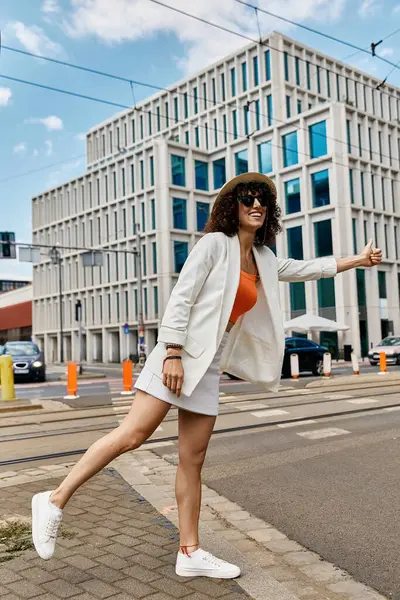A stylish woman in a white blazer and skirt hails a taxi on a European street. — Stock Photo