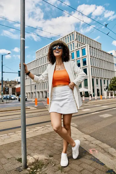 Una donna in blazer bianco e gonna posa su una strada europea. — Foto stock