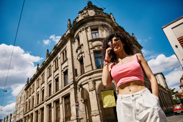 A beautiful woman, clad in stylish attire, enjoys a sunny day in Europe, taking a call. — Stock Photo