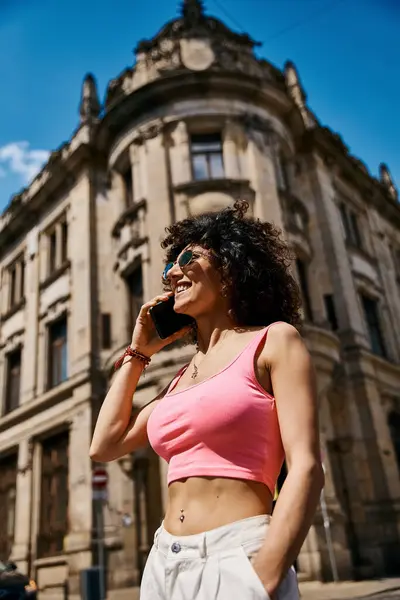 Eine Frau in stylischer Kleidung genießt einen sonnigen Tag in Europa und telefoniert. — Stockfoto