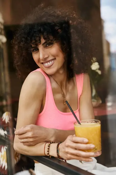 Eine Frau lächelt, während sie ein erfrischendes Getränk im Europaurlaub genießt. — Stockfoto
