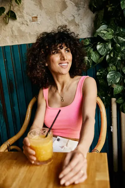 A fashionable woman with curly hair relaxes and enjoys a beverage during her European adventure. — Stock Photo