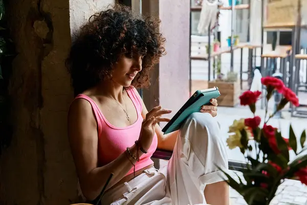 Stylish woman immersed in tablet content while seated. — Stock Photo