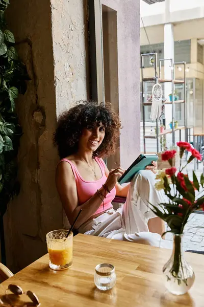 A woman enjoys a sunny afternoon in a European cafe, using her tablet and sipping on a refreshing drink. — Stock Photo