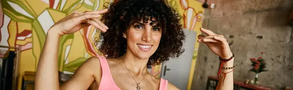 A woman with curly hair and a bright smile poses in front of colorful street art during her European travels. — Stock Photo
