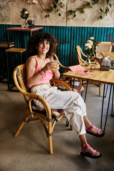 Eine Frau in stylischer Kleidung genießt ein Getränk in einem Café in Europa. — Stockfoto