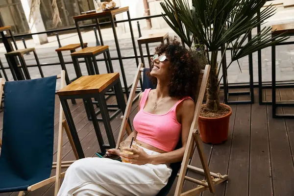 A woman in stylish attire enjoys a drink on a European patio. — Stock Photo
