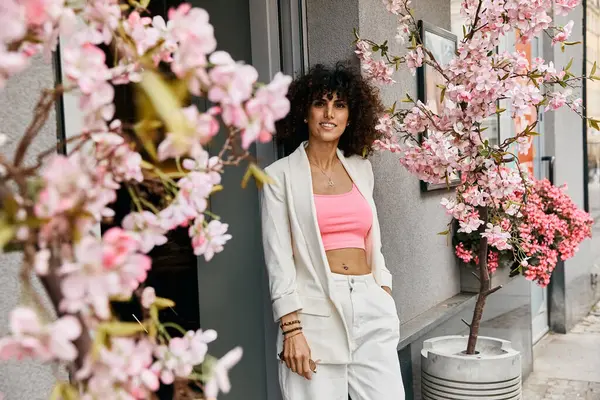 A stylish woman stands by a blooming tree in a European city. — Stock Photo