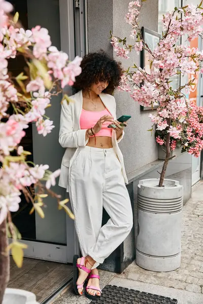Eine Frau in stylischer Kleidung erkundet die Straßen Europas und genießt die lebendige Schönheit der Kirschblüten im Frühling in voller Blüte. — Stockfoto