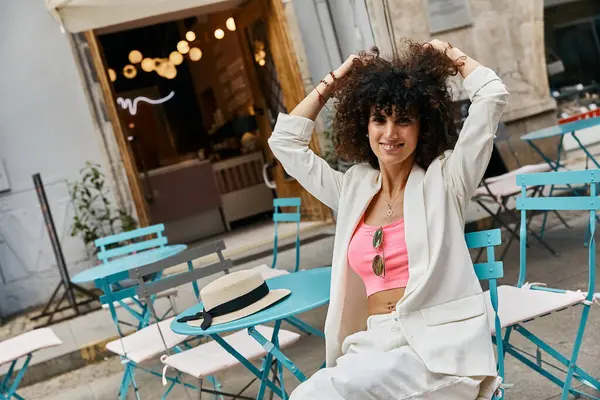 Eine stilvolle Frau in weißem Blazer und rosa Top genießt einen sonnigen Tag in Europa. — Stockfoto