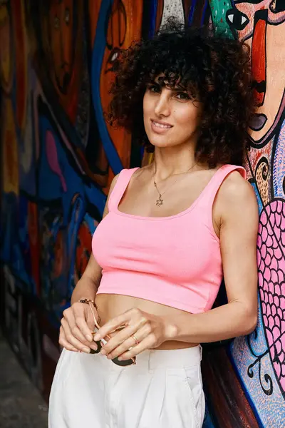 A stylish woman poses against a colorful mural in Europe. — Stock Photo