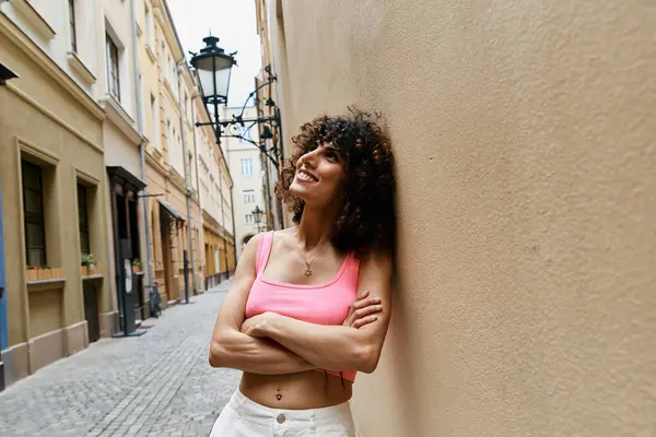 Una donna elegante si appoggia a un muro in un affascinante vicolo europeo, cogliendo le attrazioni ei suoni dei suoi dintorni. — Foto stock