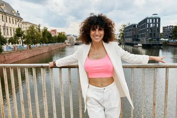Eine Frau in modischer Kleidung lehnt an einem Brückengeländer mit Blick auf einen europäischen Kanal. — Stockfoto