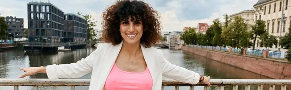 A stylish woman leans on a bridge railing, overlooking a canal in a European city. — Stock Photo