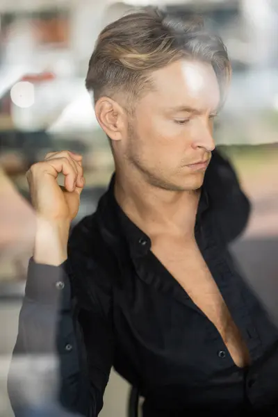 Um homem loiro bonito em traje elegante é capturado na reflexão da janela — Fotografia de Stock