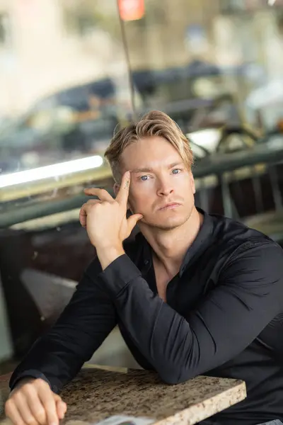 A handsome blond man in stylish attire sits thoughtfully on a street in Orlando, Florida. — Stock Photo