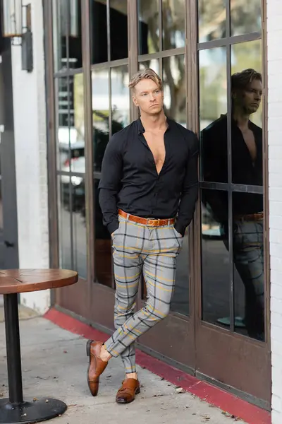 A handsome blonde man in stylish attire leans against a building in Orlando, Florida. — Stock Photo