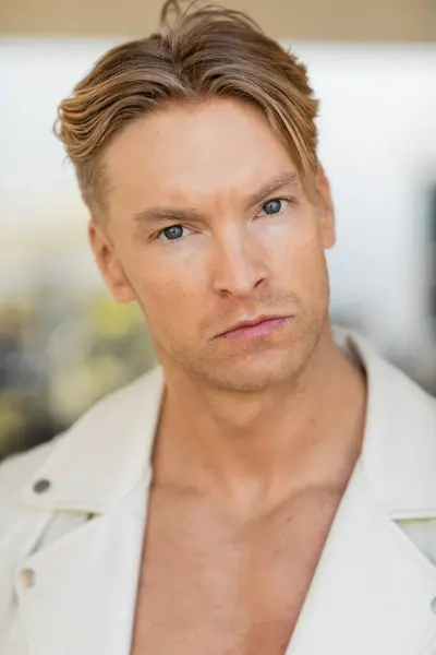 A blonde man with a serious expression poses in a white jacket on a Florida street. — Stock Photo