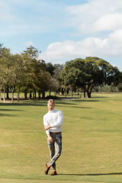 Un uomo biondo in abiti eleganti passeggia su un campo da golf a Miami. — Foto stock
