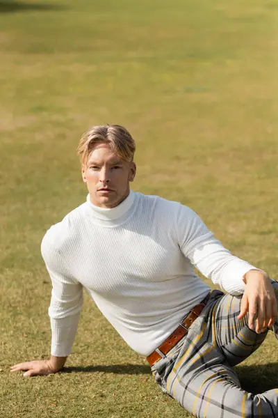 Un uomo biondo in abiti eleganti siede in un parco a Miami, Florida. — Foto stock