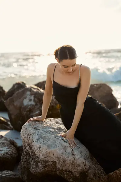 A young woman in a black sundress sits on a large rock on Miami Beach, Florida. — Stock Photo