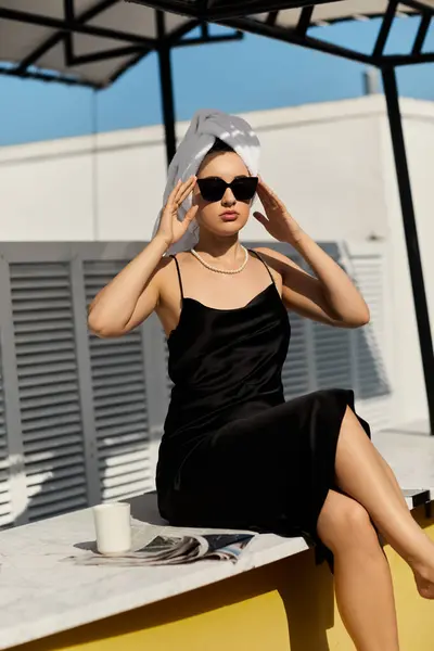 A stylish woman wearing a black slip dress and sunglasses relaxes by the pool at a Miami villa. — Stock Photo