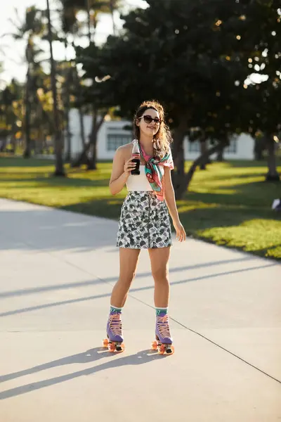 A young woman in sunglasses and a floral skirt enjoys a sunny afternoon rollerblading in Miami. — Stock Photo