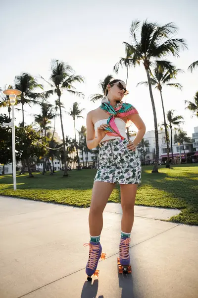 A young woman with sunglasses and a stylish outfit roller skates along a Miami sidewalk, surrounded by palm trees. — Stock Photo