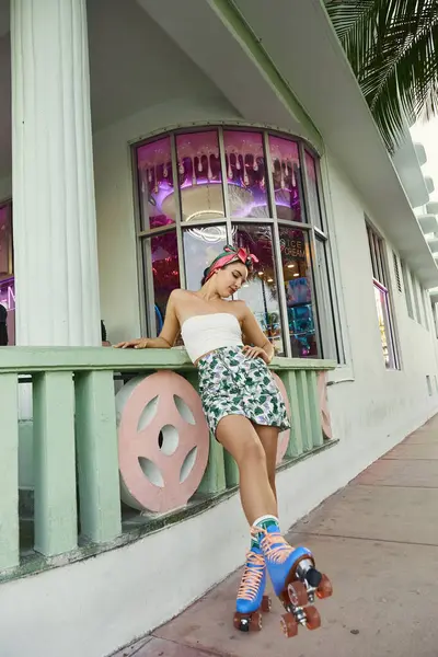 A young woman in sunglasses and a floral skirt skates through the streets of Miami. — Stock Photo