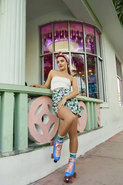 Une jeune femme avec des lunettes de soleil et des vêtements élégants pose sur des patins à roulettes à Miami. — Photo de stock