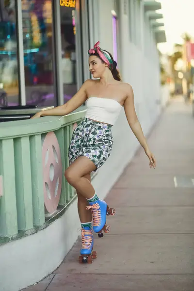 Une jeune femme en lunettes de soleil et une tenue élégante patinent dans une rue de Miami, baignée par la chaleur du coucher du soleil. — Photo de stock