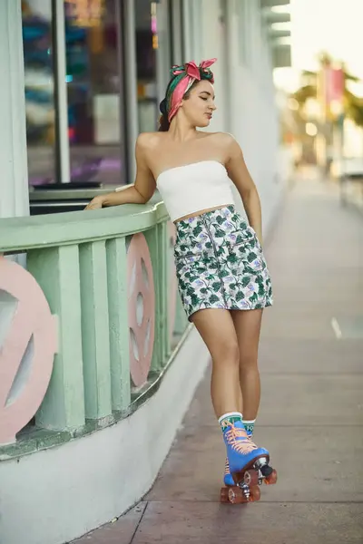 Une jeune femme en lunettes de soleil et une tenue élégante glissent sur des patins à roulettes le long d'un trottoir de Miami. — Photo de stock