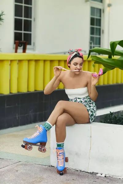 Une jeune femme en lunettes de soleil et tenue élégante est assise sur une corniche à Miami, portant des patins à roulettes. — Photo de stock