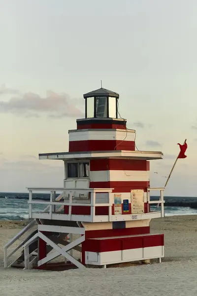 A vibrant, red and white lifeguard stand on a sandy Miami beach. — Stock Photo