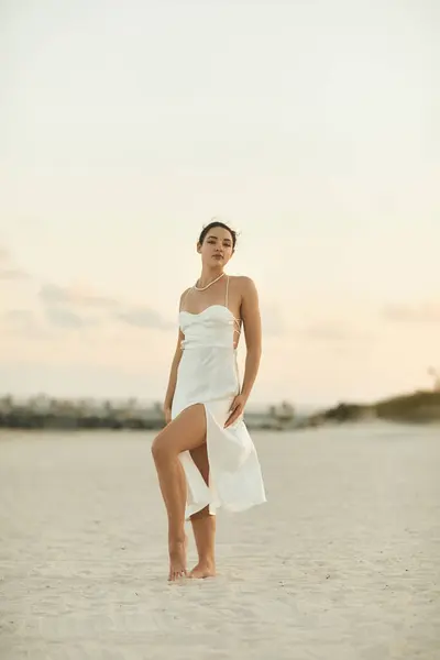 Eine junge Frau im weißen Kleid steht an einem Sandstrand in Miami, gebadet im warmen Schein der untergehenden Sonne. — Stockfoto