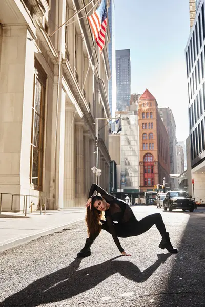 Una mujer baila con gracia en una calle de Nueva York contra edificios altos. - foto de stock