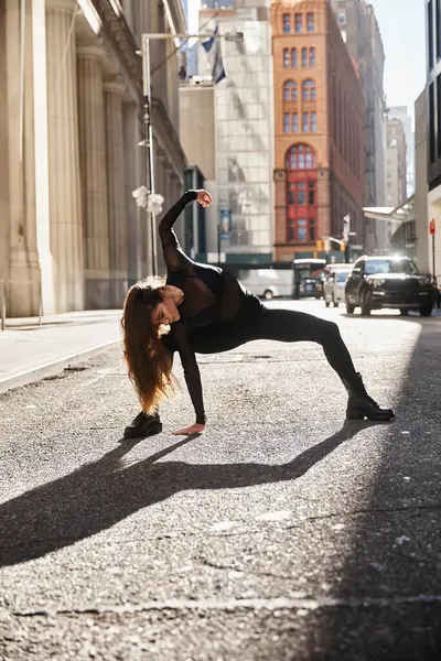 A woman dances gracefully in a NYC street, her shadow stretching long. — Stock Photo