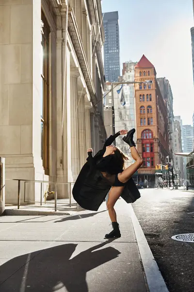 A young woman dances on a city street in New York, displaying impressive flexibility. — Stock Photo