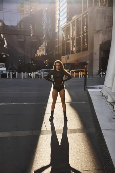 A young woman in a black outfit dances on a New York City street, bathed in sunlight. — Stock Photo