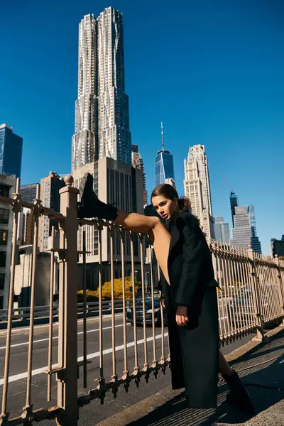 A young woman dances on the streets of New York City, her leg stretched out against a metal fence. — Stock Photo