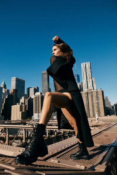 Mujer vestida de negro baila en el puente de Brooklyn contra el horizonte de Nueva York. - foto de stock